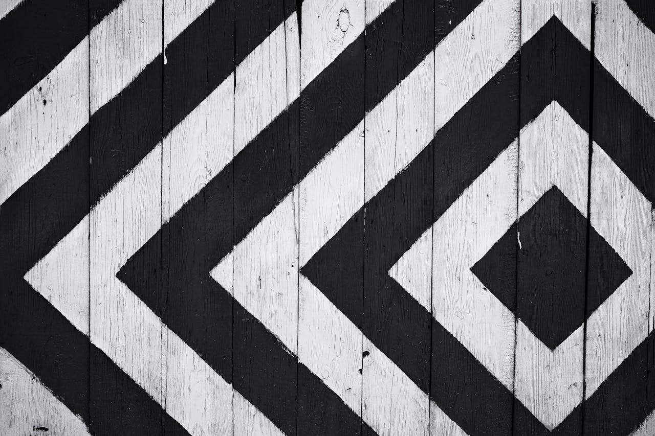 Black and white geometric pattern on wooden planks, ideal for modern design backgrounds.